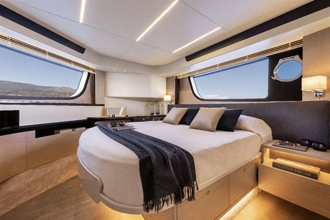 Luxurious yacht cabin featuring a round bed, stylish decor, large windows with scenic views, and ambient lighting.